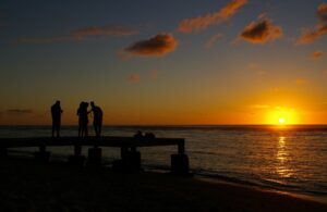 Des touristes prenant des photos du coucher de soleil sur une petite jetée de la côte ouest de l'île de La Réunion.