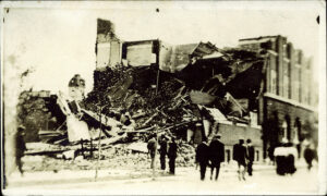 Spectateurs debout dans une rue, regardant une maison endommagée après le cyclone de Regina de juin 1912.